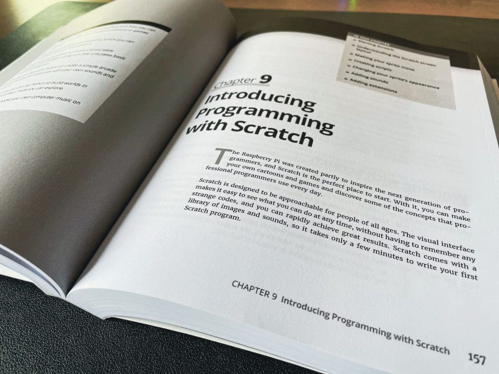 A book is open on Chapter 9, called "Introducing Programming with Scratch"